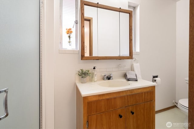 bathroom with toilet, baseboards, and vanity