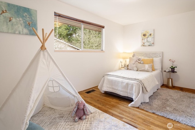 bedroom featuring visible vents, baseboards, and wood finished floors