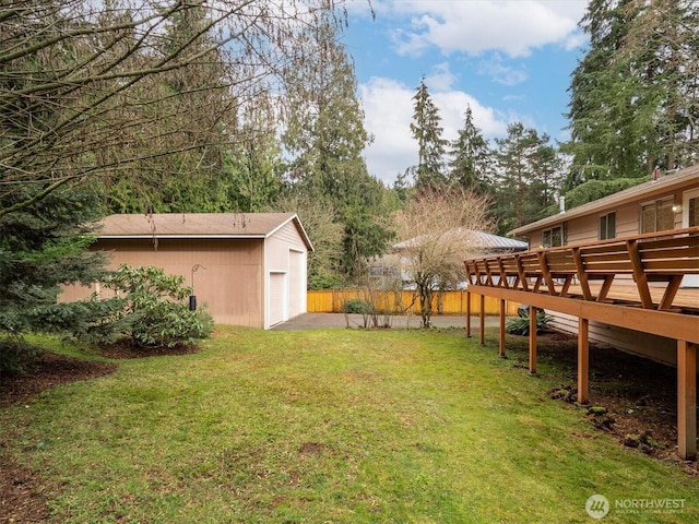 view of yard with an outbuilding, a detached garage, a deck, and fence