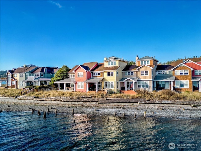 rear view of property featuring a water view, a residential view, and a chimney