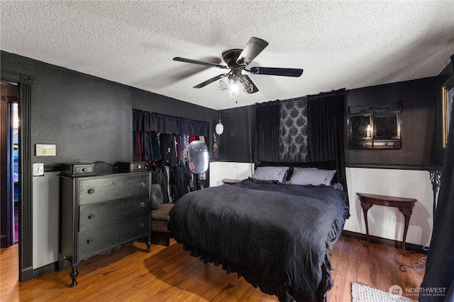 bedroom with a textured ceiling, ceiling fan, wood finished floors, and baseboards