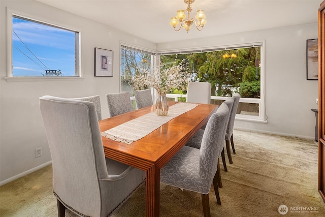 carpeted dining space with baseboards, a healthy amount of sunlight, and an inviting chandelier