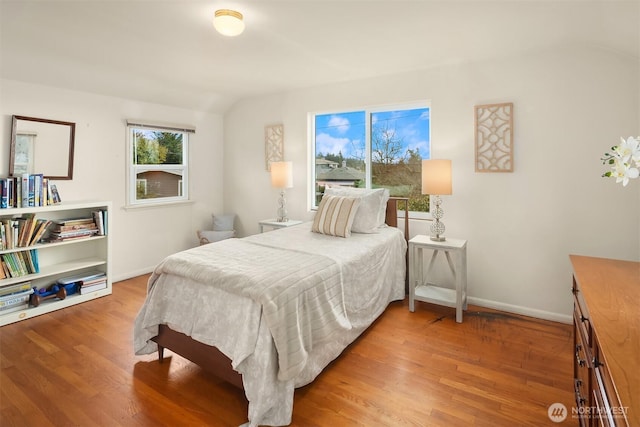 bedroom featuring lofted ceiling, wood finished floors, and baseboards