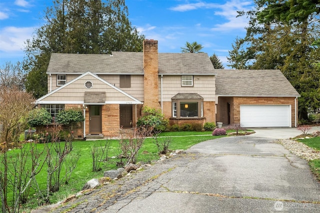 view of front of home featuring an attached garage, brick siding, driveway, a chimney, and a front yard