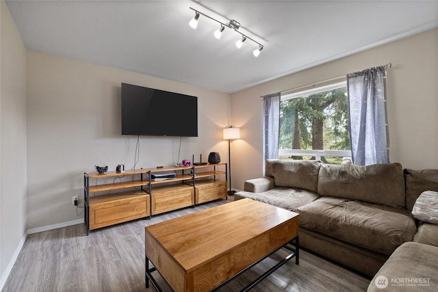 living area featuring wood finished floors, rail lighting, and baseboards