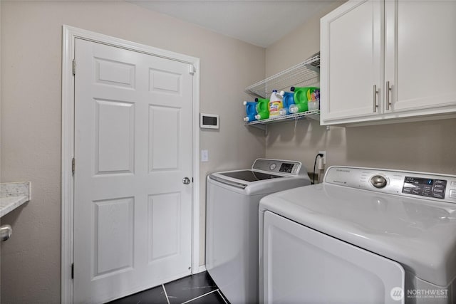 laundry room featuring cabinet space, washer and clothes dryer, and dark tile patterned flooring