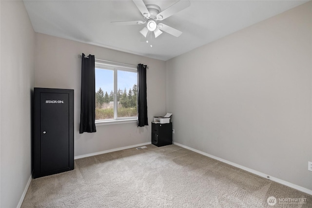 carpeted spare room featuring a ceiling fan and baseboards