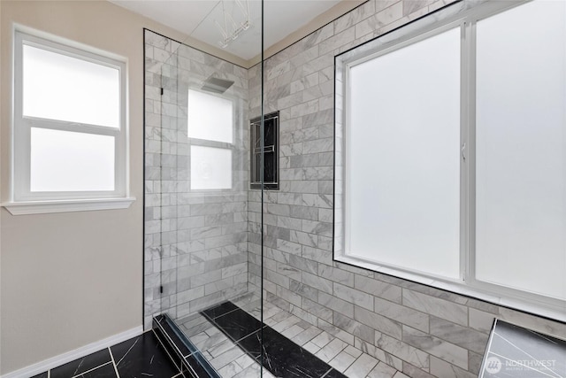 full bathroom with a tile shower and baseboards