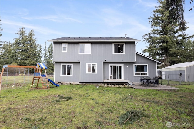 rear view of property featuring a playground, fence, crawl space, a lawn, and a patio area