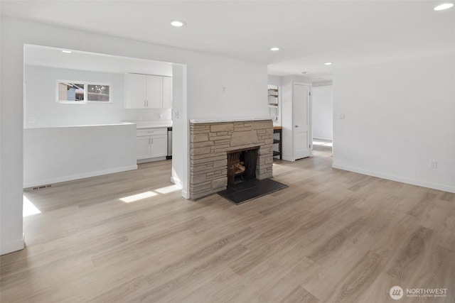 unfurnished living room featuring recessed lighting, visible vents, light wood-style flooring, a stone fireplace, and baseboards