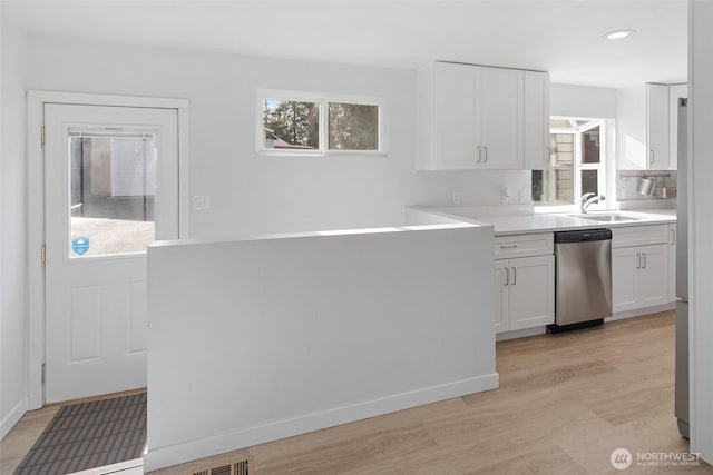 kitchen with stainless steel appliances, a wealth of natural light, white cabinets, and a sink