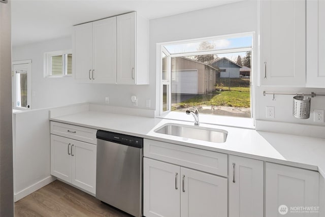 kitchen featuring wood finished floors, a sink, white cabinets, light countertops, and dishwasher