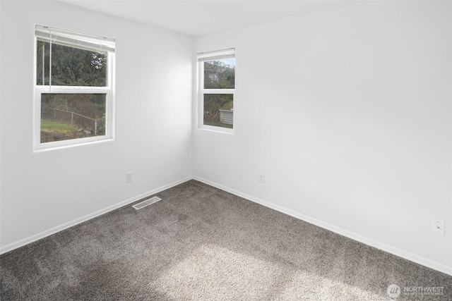 empty room featuring carpet floors, baseboards, and visible vents