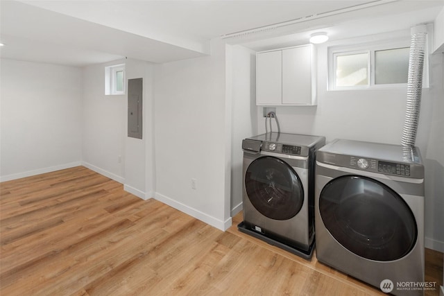 laundry room featuring cabinet space, electric panel, baseboards, independent washer and dryer, and light wood-style floors