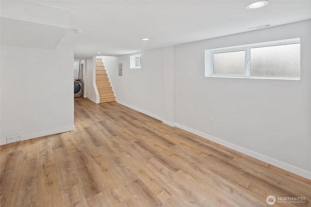 basement featuring baseboards, stairs, washer / clothes dryer, and light wood-style flooring