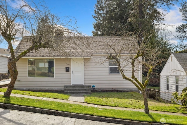 view of front of property with entry steps, a shingled roof, and a front lawn