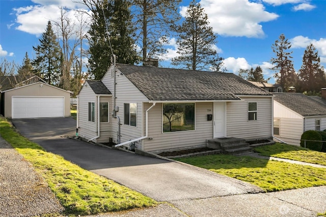 view of front facade featuring an outbuilding, a garage, a shingled roof, driveway, and a chimney