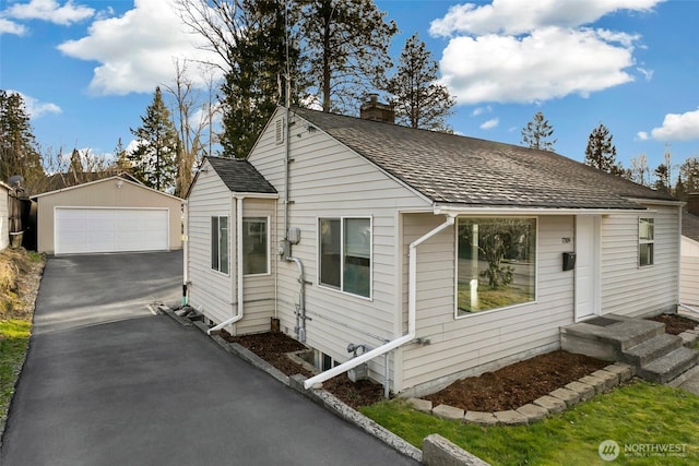 bungalow featuring a garage, an outdoor structure, and a chimney