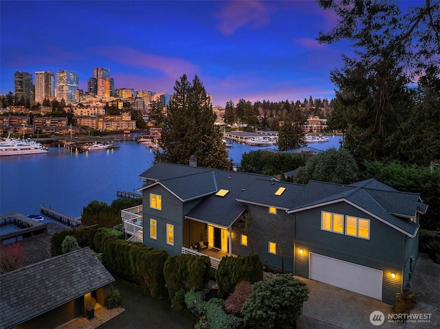 view of front of home with concrete driveway, a water view, a city view, and an attached garage