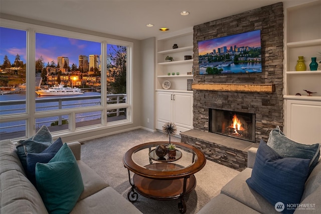 living room featuring built in shelves, recessed lighting, light carpet, a stone fireplace, and baseboards