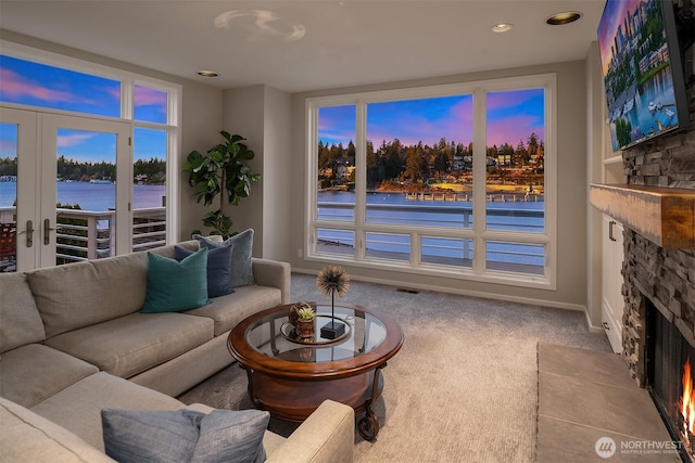 9330 SE Shoreland Dr, Bellevue, WA 98004 - living room featuring french doors, light colored carpet, visible vents, a water view, and a stone fireplace