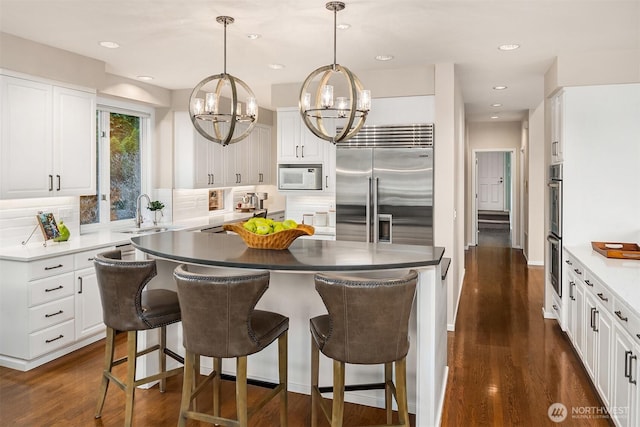 9330 SE Shoreland Dr, Bellevue, WA 98004 - kitchen featuring white cabinets, white microwave, a center island, stainless steel built in refrigerator, and a sink