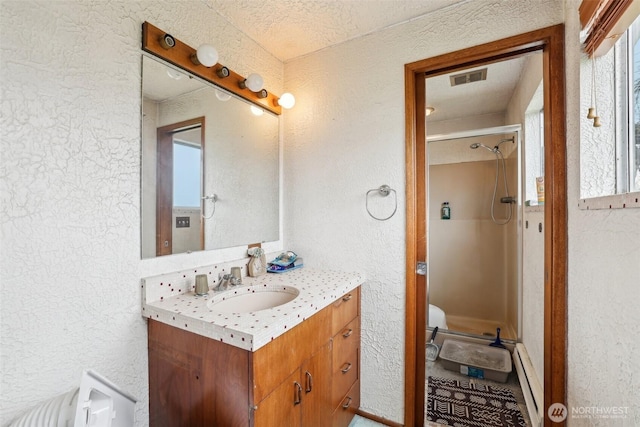 bathroom with a textured wall, visible vents, a walk in shower, and vanity