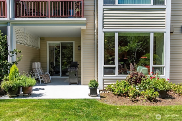 property entrance featuring a yard, a patio, and a balcony