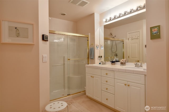 bathroom with double vanity, a stall shower, visible vents, and a sink