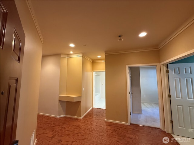 corridor with baseboards, ornamental molding, wood finished floors, and recessed lighting