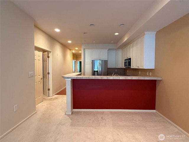 kitchen featuring tile countertops, recessed lighting, a peninsula, white cabinets, and appliances with stainless steel finishes