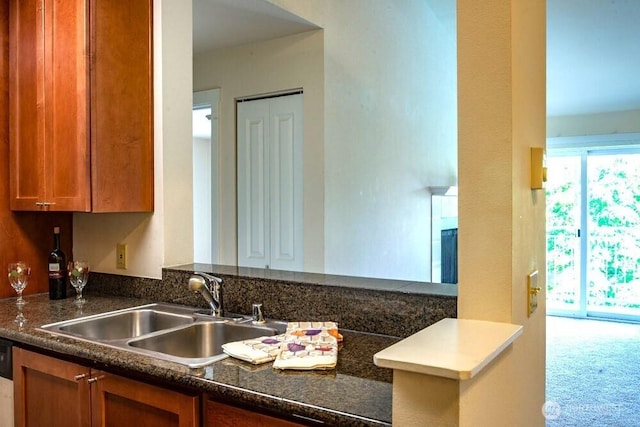 kitchen with dishwasher, a peninsula, brown cabinetry, and a sink