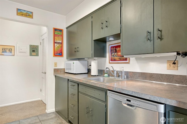 kitchen featuring white microwave, a sink, light countertops, stainless steel dishwasher, and green cabinetry