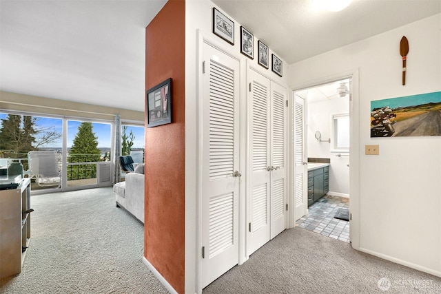 corridor featuring light carpet and baseboards