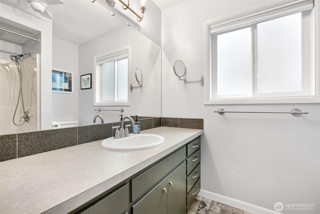 bathroom with toilet, baseboards, walk in shower, and vanity