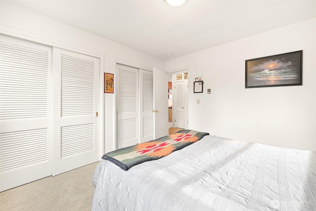 bedroom with multiple closets and light colored carpet