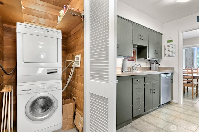 laundry area with stacked washer and dryer, light tile patterned floors, laundry area, and a sink