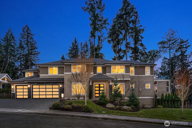 prairie-style home with driveway, a garage, and a front lawn