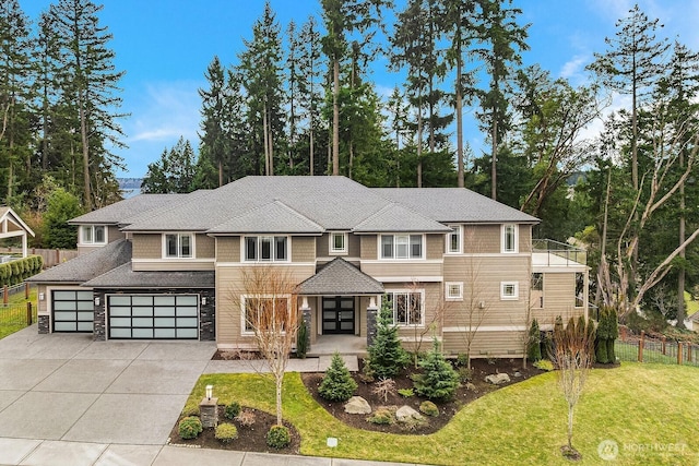 view of front facade featuring a shingled roof, concrete driveway, an attached garage, fence, and a front lawn