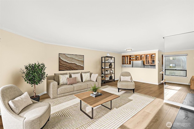 living room with ornamental molding, baseboards, and wood finished floors