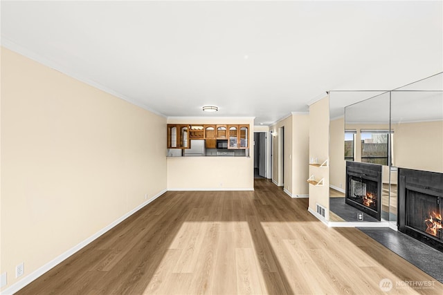 unfurnished living room with baseboards, crown molding, a multi sided fireplace, and wood finished floors