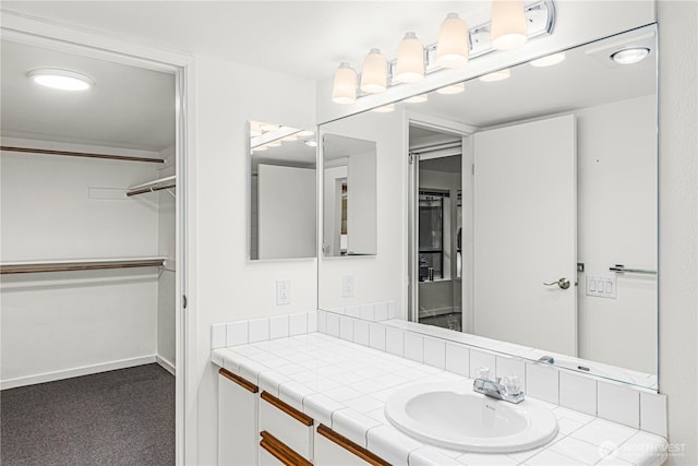 bathroom featuring a walk in closet, vanity, and baseboards