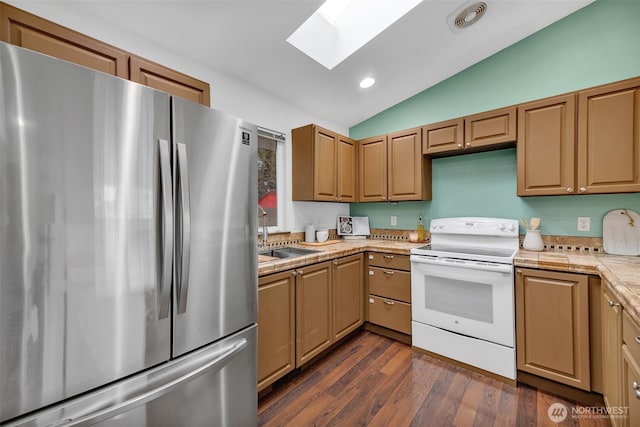 kitchen featuring white range with electric cooktop, dark wood-type flooring, a sink, freestanding refrigerator, and lofted ceiling with skylight