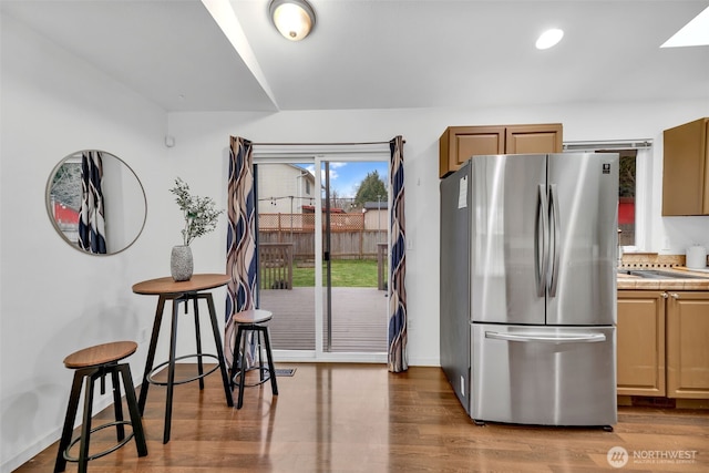 kitchen with tile counters, recessed lighting, freestanding refrigerator, wood finished floors, and baseboards