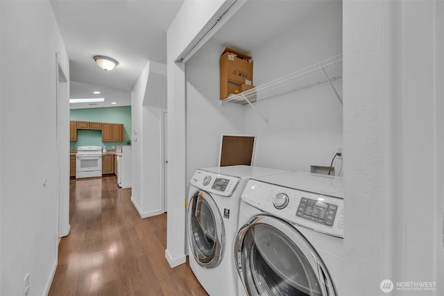 laundry area featuring laundry area, washer and clothes dryer, baseboards, and wood finished floors