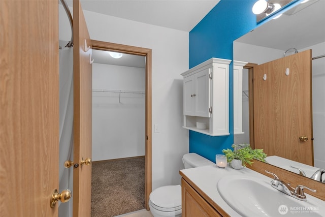 bathroom with vanity, toilet, and a walk in closet