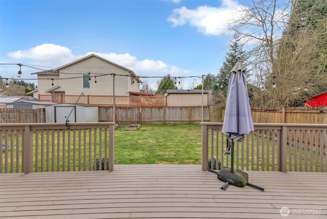 wooden terrace with a storage shed, a fenced backyard, a lawn, and an outdoor structure