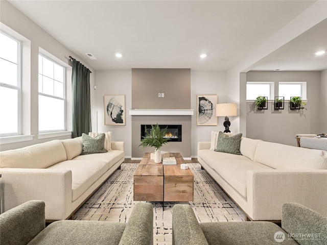 living area with recessed lighting, visible vents, baseboards, and a glass covered fireplace