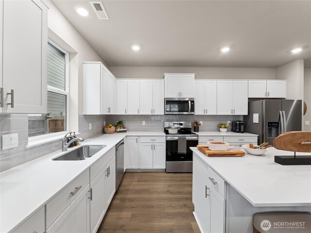 kitchen with stainless steel appliances, dark wood-style flooring, a sink, visible vents, and white cabinetry