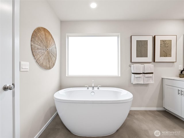 full bath with a freestanding tub, vanity, and baseboards